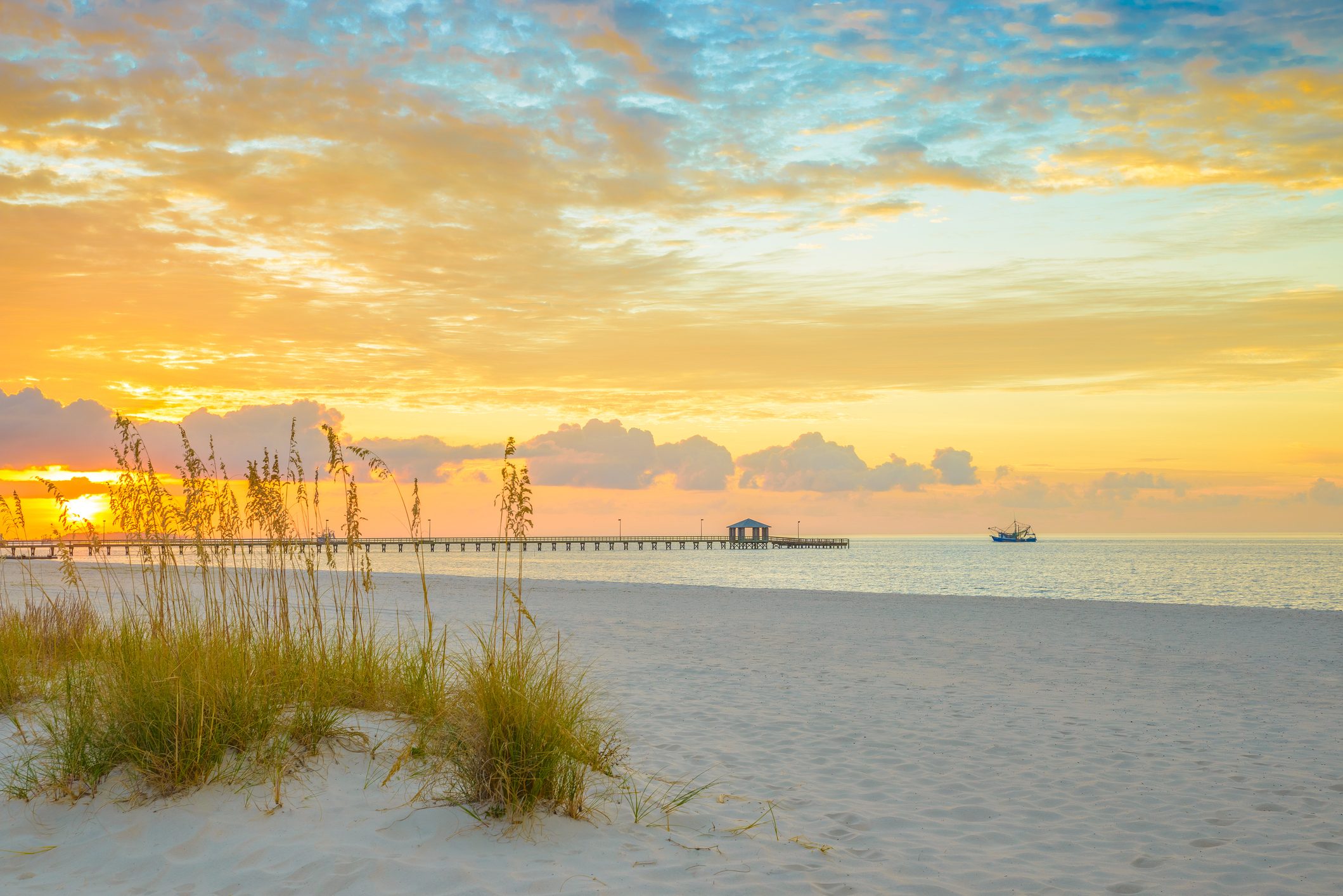 Gulfport Mississippi beach, dramtic golden sunrise, pier, shrimp boat, on the Gulf of Mexico